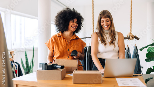 Cheerful clothing store owners preparing online orders for shipping