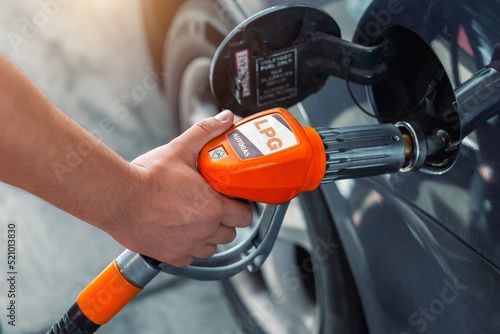 Close-up detail view of fuel autogas pump gun connected with noozle adapter to car tank to refill at car gas filling station. Refueling vehicle with liquefied lpg or lng product. Safety technology