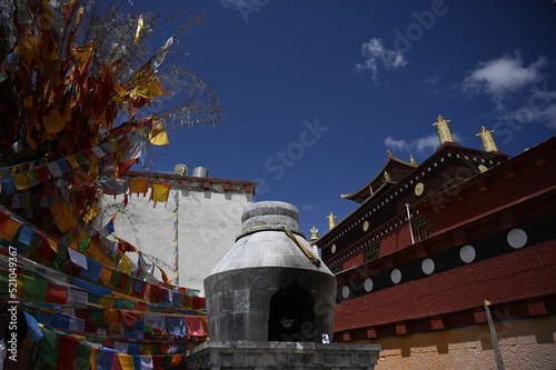 The colorful rooflines of the buildings at the Songzanlin monastery in Shangri-La, China - contrasting against the clear blue sky and adorned with many flags