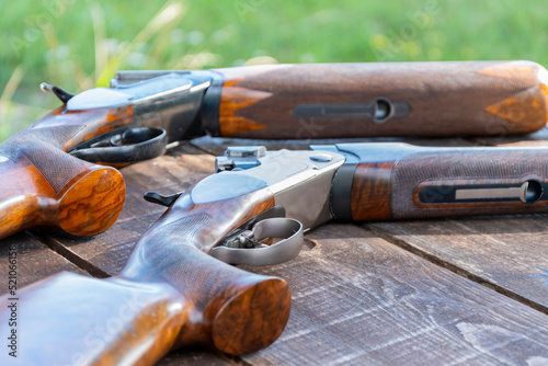 Sporting double-barreled shotguns lie on a wooden table, selective focus. bench target shooting.