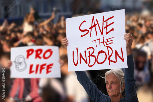 Protesters holding signs Save the unborn, Pro Life. People with placards against abortion rights at protest rally demonstration. Concept image.