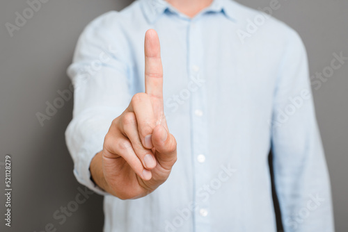 Non-verbal gesture symbol attention, wait. Close-up man showing hand sign, index finger up