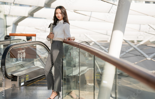 Young business woman holding a briefcase in hand riding an escalator