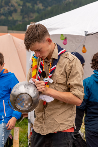 Boy scout cleaning kitchenware in a campsite