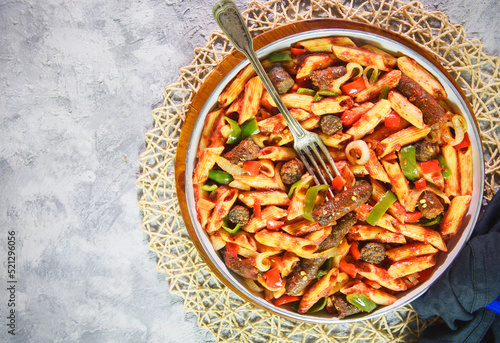 Arabic cuisine; Traditional Egyptian pasta with sausage placed in white pan on rustic background. Top view with copy space.