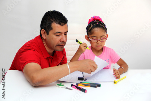 Latino dad and daughter, teacher and student draw in a notebook with colors in this back to school to improve skills with Autism Spectrum Disorder (ASD) 