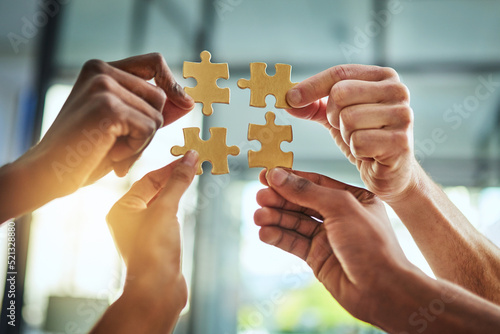 Group of business people holding puzzle pieces. Professionals connect and collaborate together inside office building. Closeup of hands, and team working together on a new strategy for success