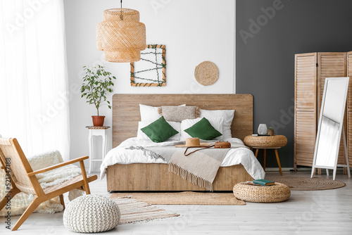 Interior of cozy bedroom with rattan poufs and mirror