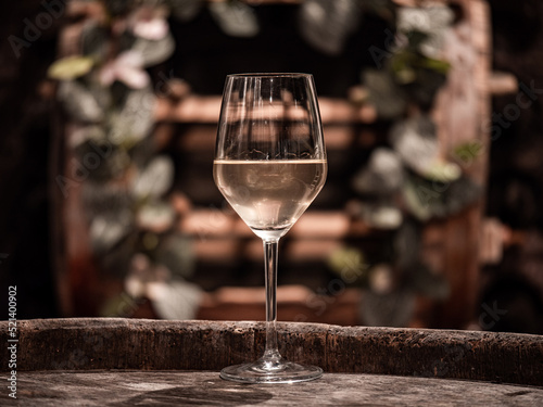 Glass with white wine and a small decorated barrel in the background