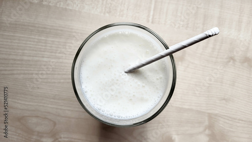 A glass of kefir on the table with a paper tube