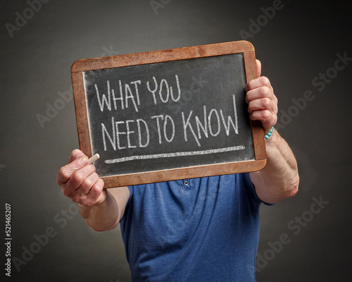 tutorial or advice concept - what you need to know - white chalk text on a vintage slate blackboard held by a man