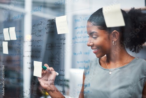 Happy, inspired and confident business woman brainstorming ideas, writing on transparent glass board with sticky notes. Powerful entrepreneur and CEO leading startup, planning company strategy.