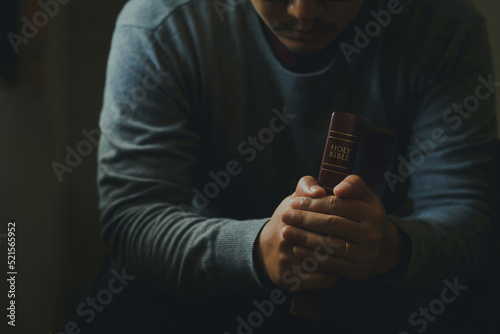 A Man praying to hold a Holy Bible. male sitting with closed eyes with the Bible in his hands, concepts for faith, spirituality, and religion.