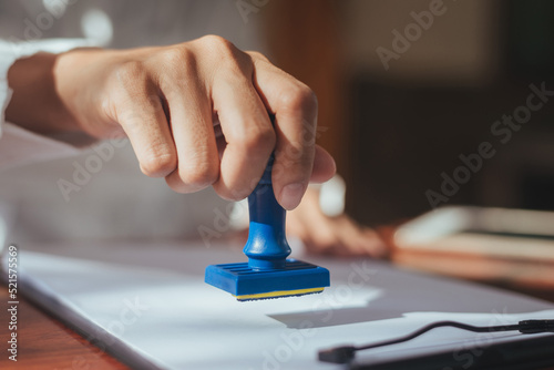 Close up of business hand stamping approved on certificate document in office, Lawyer stamping permit on paperwork at wooden desk. confirmation pass and agreement success.