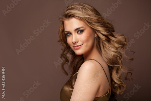 Beautiful glamorous model woman with long wavy and shiny hair against brown studio wall banner background