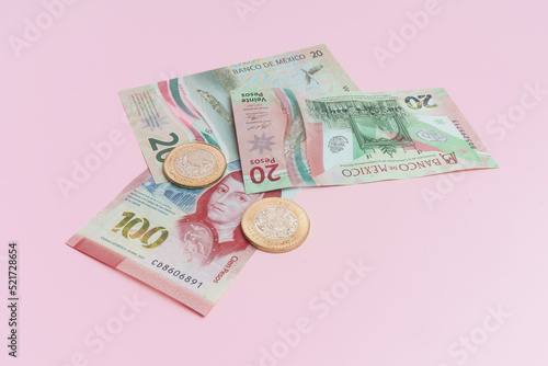 Nuevo billete de veinte pesos. Nuevo billete de cien pesos. Moneda de diez pesos. Moneda de dos pesos sobre fondo rosa. 