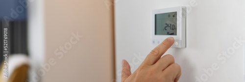 Hand sets a programmable thermostat for heating and cooling