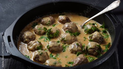 Rustic homemade Swedish meatballs in a pan with cream sauce and parsley