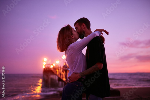 Caucasian couple in love kissing on the beach at sunset in Marbella, Spain. A guy and a girl in the popular resort of Marbella in Spain, Costa del Sol, Andalusia region, Malaga province.