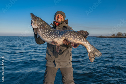 Successful pike fishing. Happy fisherman hold huge muskie fish