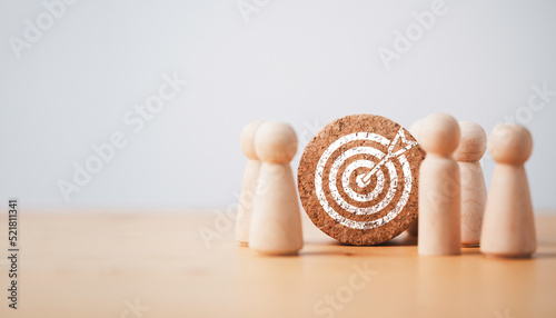 Wooden miniature figures standing with dartboard and arrow for setup business objective target and goal concept.