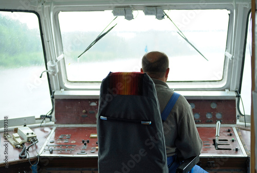 Man helmsman driving the pleasure boatboat in the wheelhouse. Chernigiv, Ukraine