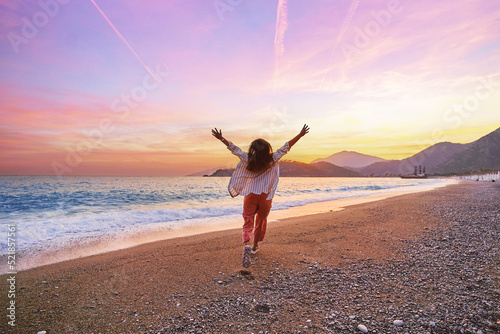 Happy carefree one alone joyful girl running with open arms on the beach at sunset. Beautiful moment life vacation