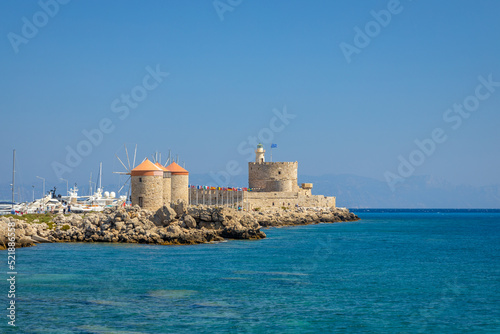 Windmills of Mandraki harbour and Saint Nicholas Fortress in Rhodes town, Greece, Europe.