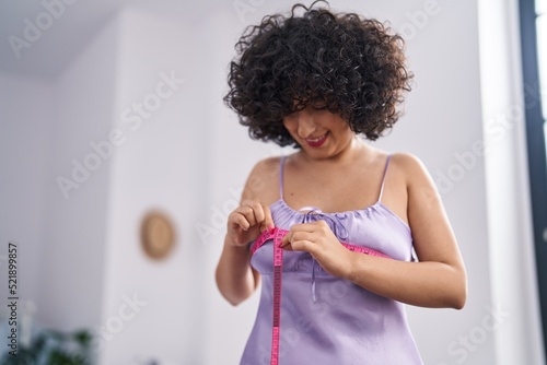 Young middle east woman measuring brest size using tape measure at bedroom