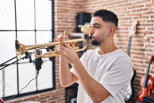 Young arab man musician playing trumpet at music studio