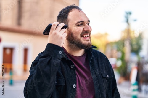 Young hispanic man smiling confident listening audio message by the smartphone at street