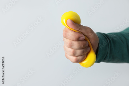 Man squeezing antistress ball on light background, closeup. Space for text