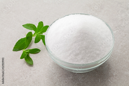 natural sugar substitute sweetener in a glass bowl with fresh stevia leaves.