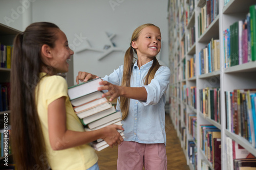 Two schoolgirls choosing educational literature in the library