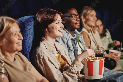 Selective focus of diverse group of people having fun watching film and eating popcorn at cinema on weekend
