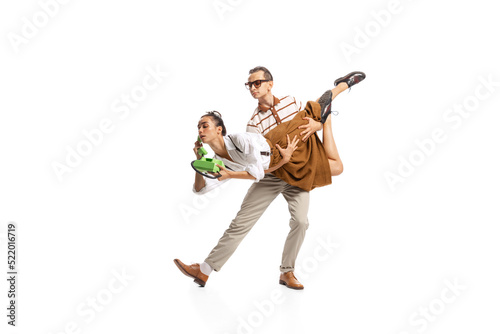 Portrait of stylish man holding woman in retro clothes talking on vintage phone isolated over white studio background