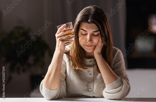 alcoholism, alcohol addiction and people concept - drunk woman or female alcoholic drinking whiskey at home