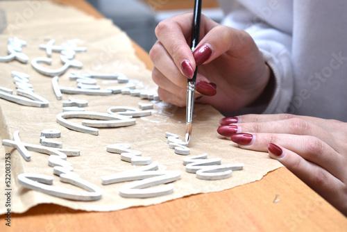 a woman painting some wooden figures with brushes