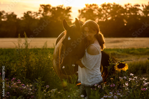 Frau mit Pferd bei Sonnenuntergang im Blumenfeld