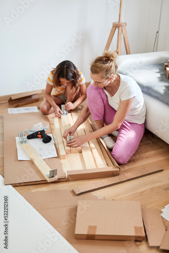 Mother and daughter assembling new furniture - moving in into a new home.