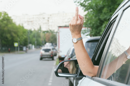 Woman driving a car showing middle finger. Angry woman demonstrating fuck you off sign from open window.