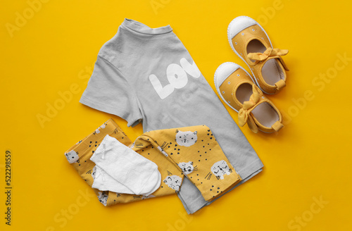 Stylish child clothes and shoes on yellow background, flat lay