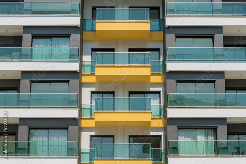 The front of a modern apartment building with glass balconies.