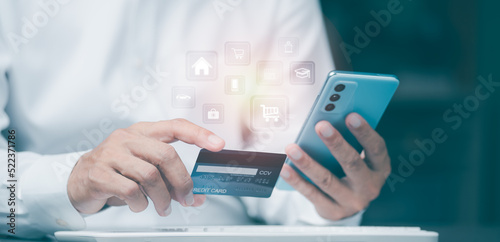 Young businessman using credit card to make financial transactions via smartphone, payment concept with wireless communication technology, focus on consumer safety and cashlessness.