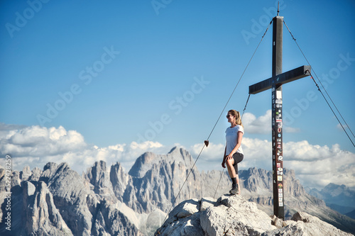 Frau am Gipfelkreuz mit Bergpanorama im Hintergrund