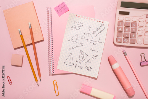 On a pink background, pink school supplies, a calculator, cheat sheets