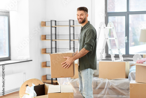 moving, people and real estate concept - happy smiling man holding box with stuff at new home