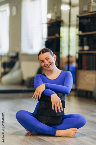 Portrait of a beautiful young European woman doing sports in the studio. A girl in leggings and a blue top. Looks at the camera. Yoga, fitness, sports.