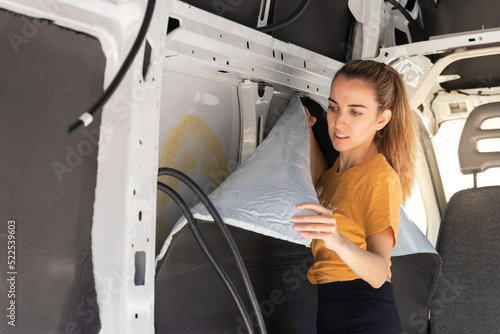 Young woman concentrated looking to the self adhesive rubber insulation in a camper van convertion