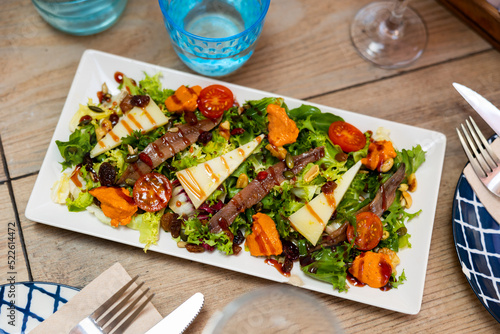 Traditional Mediterranean salad of fresh lettuce with romesco sauce, anchovy fillets and cheese slices garnished with nuts, raisins and seeds and dressed with balsamic vinaigrette